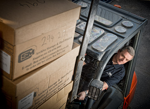 Forklift driver stacking boxes in a storage depot in Kent