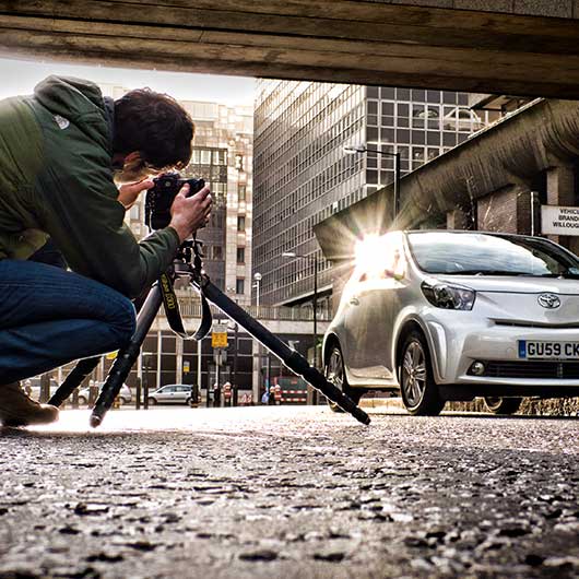 Car photographer taking a picture of a small car in a street in London