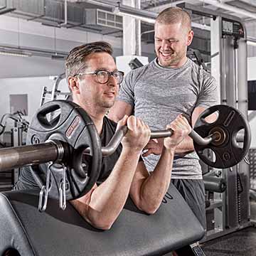 Personal trainer teaching use of weights in an Essex gym