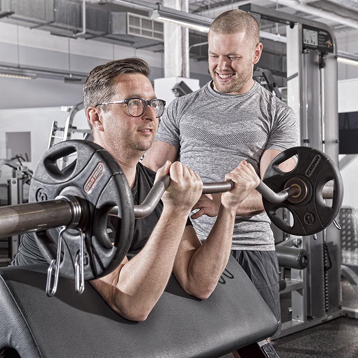 Personal trainer teaching use of weights in an Essex gym