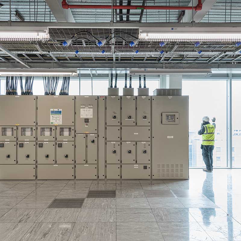 Image of worker making a call next to large electrical boxes