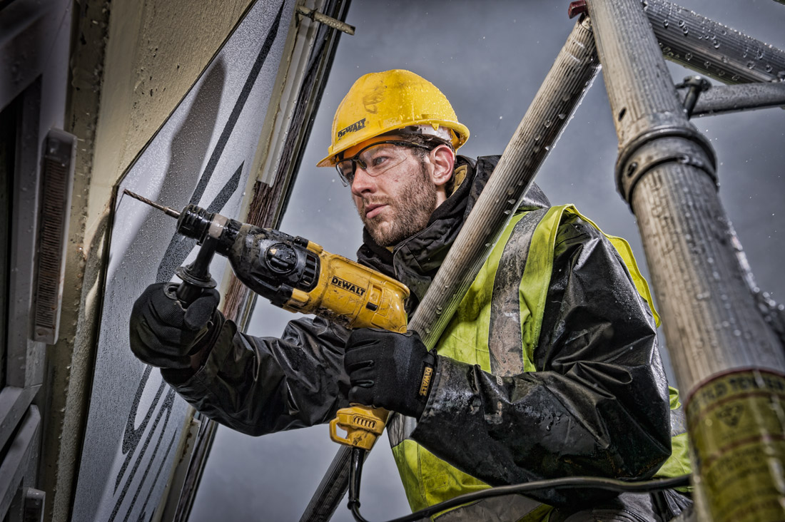 deWalt photography of worker using a drill outside in the rain
