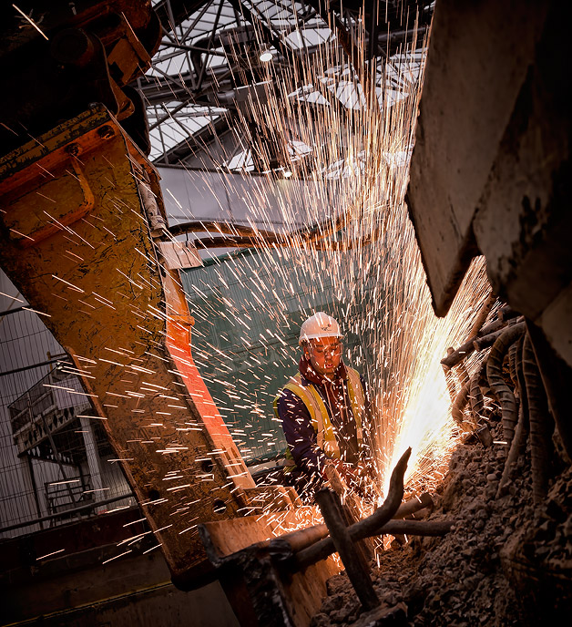 Demolition worker cutting steel bars creating sparks