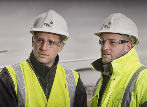 Construction workers at an airport with aircraft in the background