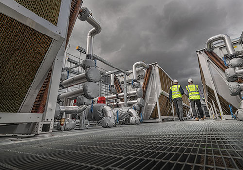 Refrigeration units being inspected on the roof of a data center.