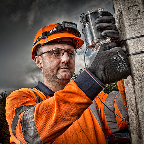 An industrial photographer fixing a camera with a small aperture lens for technical photography.