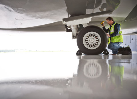 Technician checking undercarriage of jet airplane at Stansted Airport in Essex