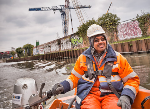 Worker in a boat on the River Lea in Stratford, East London