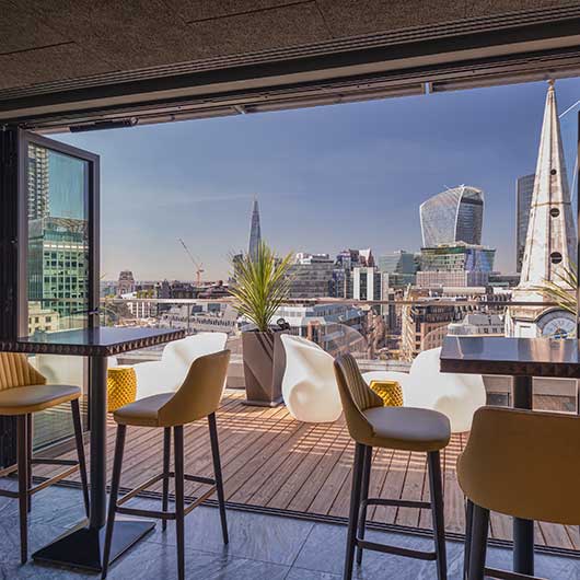 A roof top bar in central London overlooking large buildings