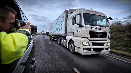 Photograph of a photographer taking a picture of a lorry from a car on a motorway