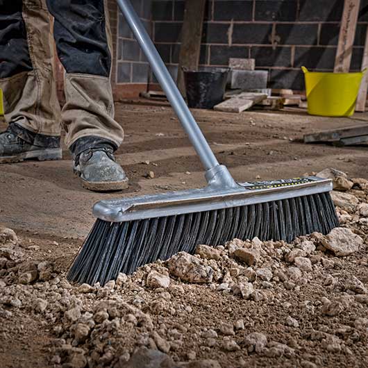 A broom being used to sweep rubble on a construction site