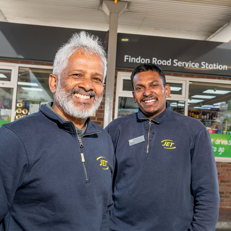 Owner and staff at a filling station outside of the shop near the petrol pumps