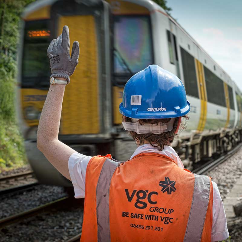 Rail worker signalling to a train driver on the tracks in Kent